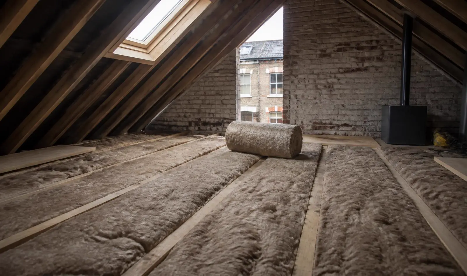 Loft insulation being installed between timber joists in a Victorian London property, one of the most cost-effective EPC improvements for landlords.