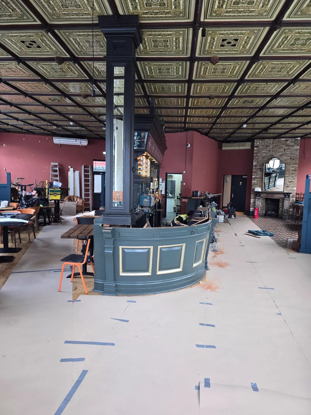 Slate-grey bar front with gold panel details during finishing works